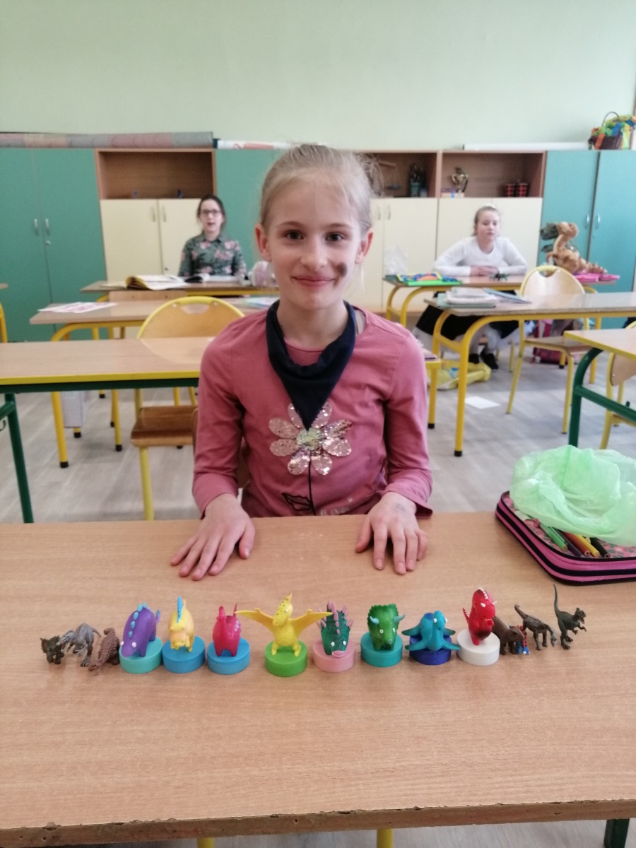 Dziewczynka prezentująca figury dinozaurów